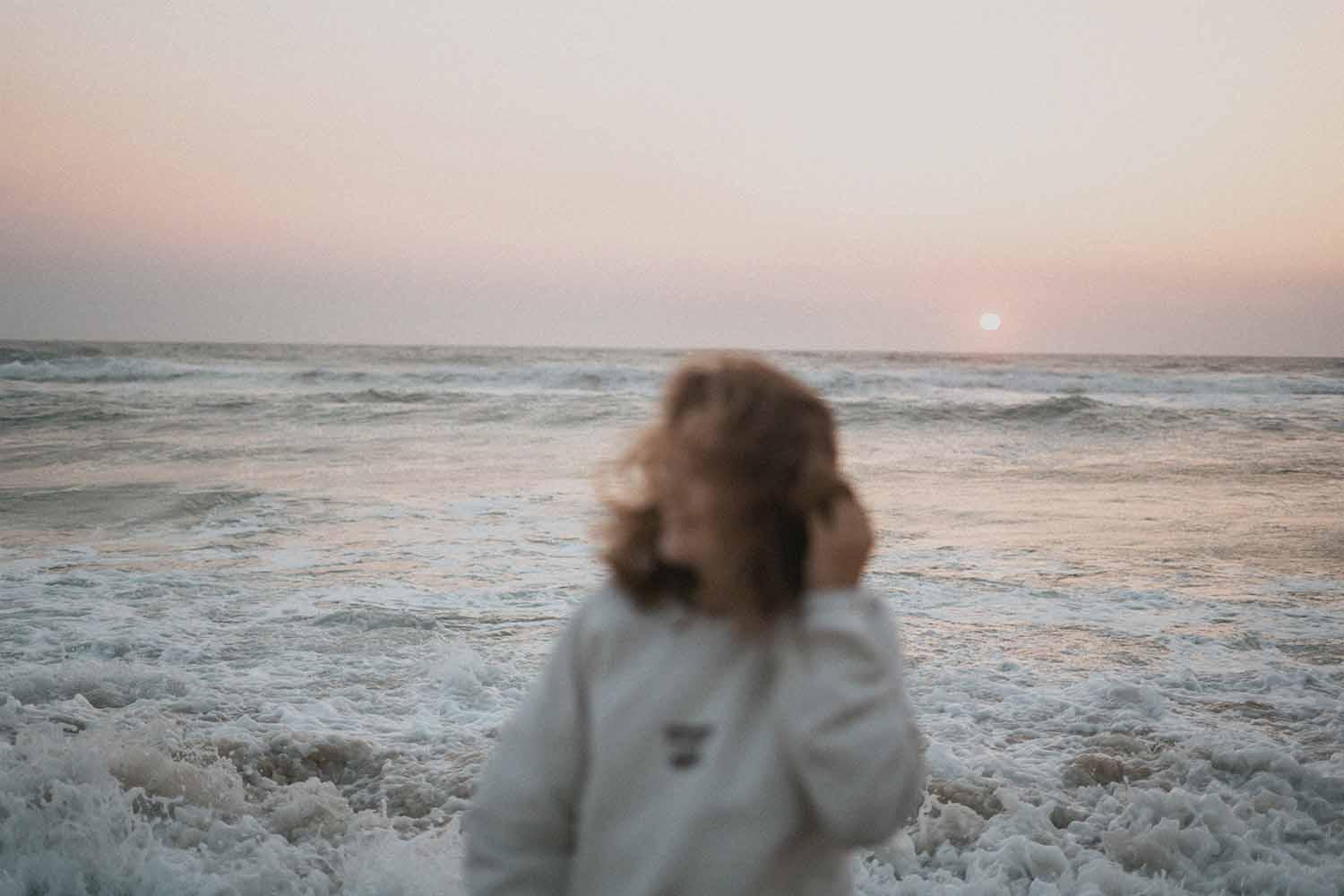 En stressfri kvinde på stranden i solnedgangen